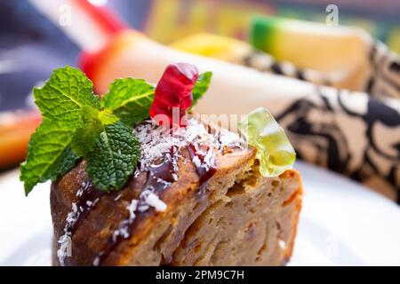 Gummibären, die mit Bananenbrot auf einem Esstisch spielen. Stockfoto