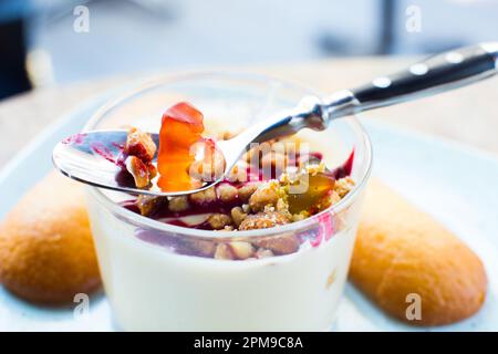 Gummibären, die auf einem Esstisch in einem Joghurt-Dessert spielen. Stockfoto