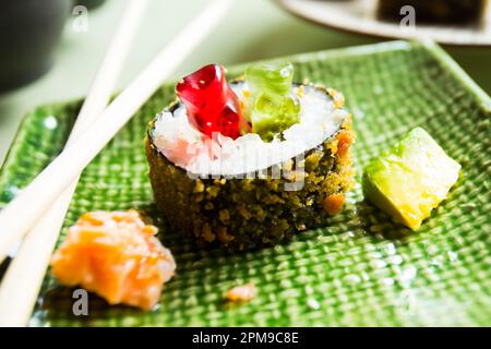 Gummibären, die auf einem Esstisch mit einem Sushi-Hot-Roll spielen. Stockfoto