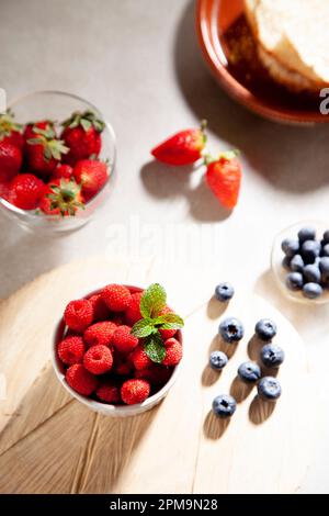 Ein Blick von oben auf eine Auswahl saftiger Beeren auf einer rustikalen Holztischfläche Stockfoto