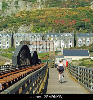 Barmouth Seite der viktorianischen Klasse II denkmalgeschützten einspurigen hölzernen Eisenbahnbrücke mit einer Reihe ähnlicher Häuserblocks einschließlich Gästehäuser und anderen Ferienunterkünften mit felsigem Hintergrund und Zugang zu atemberaubendem Blick zurück über die Flussmündung des Afon Mawdach und Eisenbahnbrücke (Z. B. Alamy Ref ABY35C & ABYD8C). Leichter Zugang zu erlaubten Wander- und Radtouren auf der angrenzenden öffentlichen Fußgängerbrücke in Gwynedd in North Wales UK Stockfoto