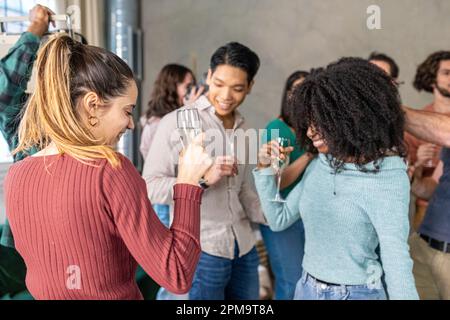 Eine große Gruppe von Menschen organisiert eine Party mit Musik und Tanz in einem privaten Haus, multiethnische Freunde tanzen zusammen Stockfoto