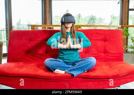 Erwachsene Frau, die Meditation und Yoga mit Hilfe eines Zuschauers für virtuelle Realität praktiziert Stockfoto