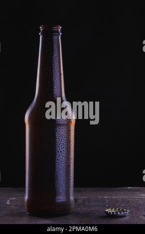 Kalte Flasche Bier auf einer Schieferoberfläche und schwarzem Hintergrund mit Tröpfchen auf der Flasche. Stockfoto