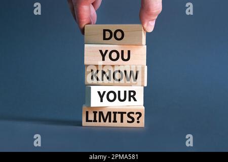 Kennen Sie das Limitsymbol? Konzeptbegriffe kennst du deine Grenzen bei Holzblöcken? Wunderschöner grauer Tischhintergrund. Geschäftsmannshand. Geschäfte Stockfoto
