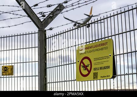 Internationaler Flughafen Düsseldorf, Sicherheitszaun an der Flughafengrenze, Start- und Landebahn, Hinweis auf das Verbot von Drohnenflügen auf Flughäfen, Flugzeuge auf App Stockfoto