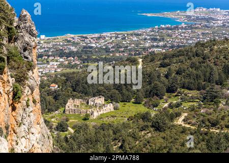Die Ruine des "Tarihi Manastır" (Historisches Kloster), gesehen vom Beşparmak-Pfad, liegt in einer Kiefernlichtung in den Fünf-Finger-Bergen (Beşparmak-Gebirge), Türkische Republik Zypern (TRNC). Im Hintergrund erstrecken sich die Küstenstadt Girne/Kyrenia und das Mittelmeer bis zum Horizont. Stockfoto