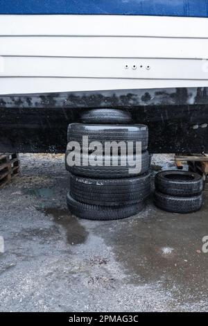 Ein Stapel alter Reifen, der ein Boot an Land trägt Stockfoto