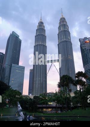 KUALA LUMPUR, MALAYSIA - 10. November 2015: Reflektieren die Petronas Twin Towers im Teich im KLCC Park, der gesäumt ist von Luxushotels und shopp Stockfoto