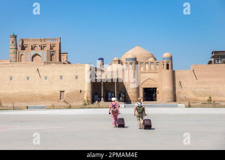 KHIVA, USBEKISTAN - 05. SEPTEMBER 2022: Zwei Touristen nähern sich den Toren der Altstadt von Ichan-Kala. Khiva, Usbekistan Stockfoto