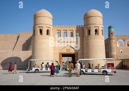 KHIVA, USBEKISTAN - 07. SEPTEMBER 2022: Tourwagen mit Touristen an den Mauern der Altstadt von Ichan-Kala. Khiva, Usbekistan Stockfoto