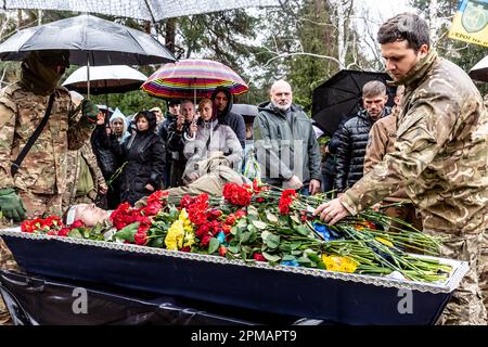 Freunde und Familie liegen auf dem Lisove-Friedhof in Kiew, der Hauptstadt der Ukraine am 12. April 2023, während einer Beerdigung von Evgeny Yakovlev, 42, einem Soldaten, der von russischen Streitkräften an der Ostukrainischen Front in einem Kampf getötet wurde, Blumen. Der Lisove Friedhof ist, wo die meisten gefallenen Armeeangehörigen aus Kiew begraben sind. Da die Invasion der Ukraine in vollem Umfang durch die russischen Streitkräfte andauert, verursacht der Kampf im Osten der Ukraine eine sehr hohe Zahl von Opfern, obwohl die genauen Zahlen unbekannt sind. Die Ukraine bereitet sich auf eine Frühjahrsoffensive zur Rückeroberung des von Russland besetzten Landes vor. (Foto: Dominika Zarzycka/Sipa USA) Stockfoto