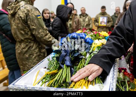 Freunde und Familie liegen auf dem Lisove-Friedhof in Kiew, der Hauptstadt der Ukraine am 12. April 2023, während einer Beerdigung von Evgeny Yakovlev, 42, einem Soldaten, der von russischen Streitkräften an der Ostukrainischen Front in einem Kampf getötet wurde, Blumen. Der Lisove Friedhof ist, wo die meisten gefallenen Armeeangehörigen aus Kiew begraben sind. Da die Invasion der Ukraine in vollem Umfang durch die russischen Streitkräfte andauert, verursacht der Kampf im Osten der Ukraine eine sehr hohe Zahl von Opfern, obwohl die genauen Zahlen unbekannt sind. Die Ukraine bereitet sich auf eine Frühjahrsoffensive zur Rückeroberung des von Russland besetzten Landes vor. (Foto: Dominika Zarzycka/Sipa USA) Stockfoto