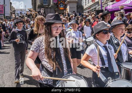 Schulkinder, die bei der Parade des Mazey Day im Rahmen des Golowan Festivals in Penzance in Cornwall im Vereinigten Königreich Trommeln. Stockfoto