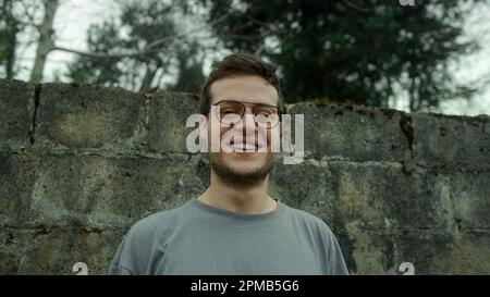 Attraktiver, lächelnder junger Mann mit Brille, der in Nahaufnahme auf die Kamera schaut Stockfoto