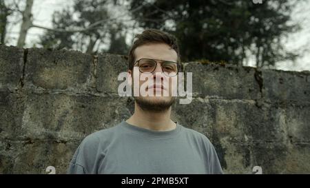 Junger Mann mit Brille, der in Nahaufnahme Porträtaufnahmen auf die Kamera schaut Stockfoto