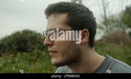 Abgelenkter gutaussehender junger Mann, der draußen seufzt und frustriert Stockfoto