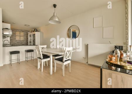 Küche und Essbereich in einem kleinen Apartment mit Holzfußboden, weißen Wänden, Holzfußboden und einem großen Spiegel Stockfoto