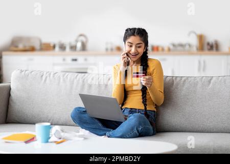 Online-Bestellung. Glückliche inderin mit Kreditkarte und telefoniert mit Handy Stockfoto