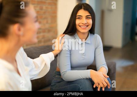 Unterhaltung und Unterstützung von Mädchen. Junge spanierin, die Probleme mit ihrer besten Freundin teilt, auf dem Sofa sitzt und redet Stockfoto