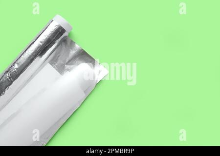 Backpapierrollen und Aluminiumfolie auf grünem Hintergrund Stockfoto