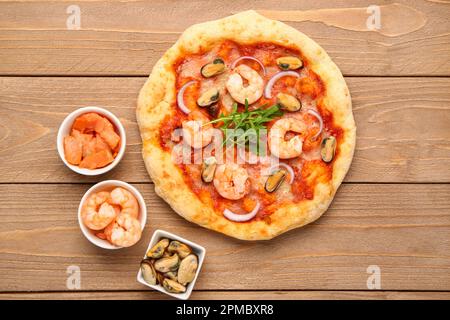 Leckere Pizza mit Meeresfrüchten und Zutaten auf Holzhintergrund Stockfoto