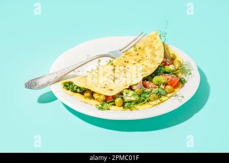 Leckeres Omelett mit Gemüse auf blauem Hintergrund Stockfoto