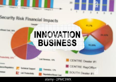 Geschäftskonzept. Auf Diagrammen und Grafiken liegt zerrissenes Papier mit der Aufschrift „Innovation Business“. Diagramme und Diagramme sind verschwommen. Stockfoto