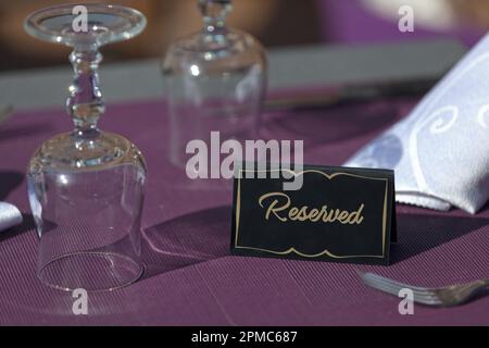 Tisch auf der Terrasse eines Restaurants mit einem Schild mit der Aufschrift "reserviert". Stockfoto