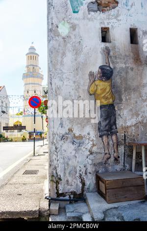 Street-Art-Wandjunge, der in George Town auf Penang Island in Malaysia ein Wandporträt aufnimmt Stockfoto