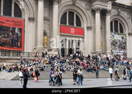 An einem sonnigen Frühlingsnachmittag im Jahr 2023 in New York City, USA, versammeln sich auf den vorderen Stufen des Metropolitan Museum of Art große Besuchermassen Stockfoto