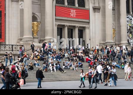 An einem sonnigen Frühlingsnachmittag im Jahr 2023 in New York City, USA, versammeln sich auf den vorderen Stufen des Metropolitan Museum of Art große Besuchermassen Stockfoto