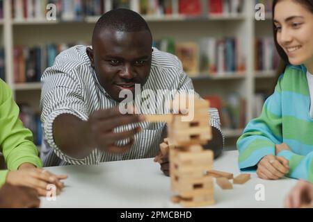 Nahaufnahme eines fokussierten schwarzen Mannes, der in der Bibliothek und in einem beweglichen Teil des Balancesturms spielt Stockfoto