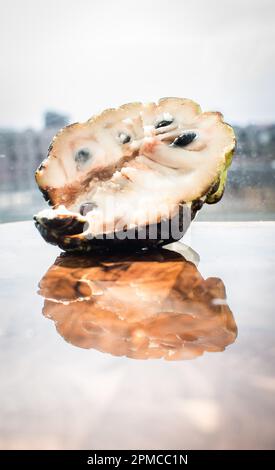 Nahaufnahme eines Puddingapfels, einer exotischen Frucht mit einem Vanilleduft und süßem Geschmack. Die äußere Textur sieht fast wie Schuppen aus, ist aber weich und weiß Stockfoto
