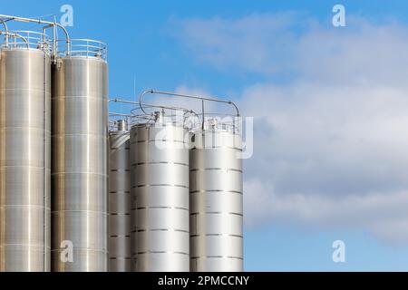 Edelstahlsilos am blauen Himmel. Lagerhäuser zur Lagerung von Kunststoffen und Schüttgut. Stockfoto