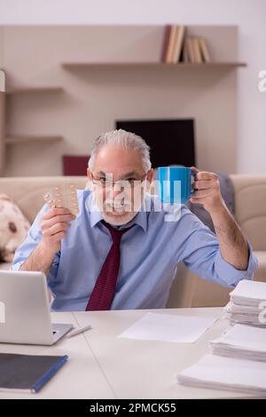 Alter Geschäftsmann, der zu Hause unter Pandemie leidet Stockfoto