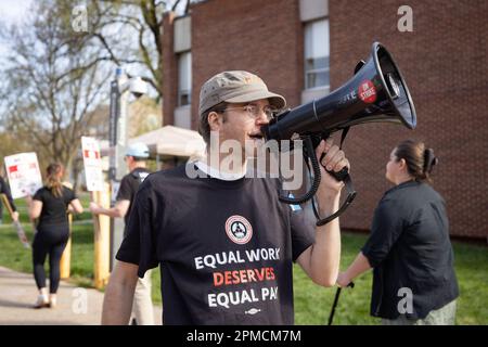 New Brunswick, New Jersey, USA. 12. April 2023. Ein Demonstrant mit einem Megafon führt Gesänge mit Rutgers Studenten und Dozenten an, während sie an einem Streik auf dem Hauptcampus der Universität in New Brunswick teilnehmen. Die drei Fakultätsgewerkschaften, die etwa 9.000 Arbeiter an der Rutgers University, der staatlichen Universität von New Jersey, repräsentierten, streikten, nachdem sie in Verhandlungen mit der Regierung von Rutgers-Präsident Jonathan Holloway keinen Vertrag zustande gebracht hatten. Der Rundgang ist der erste in der 257-jährigen Geschichte der öffentlichen Universität und folgt fast einem Jahr der Verhandlungen um höhere Löhne und B. Stockfoto