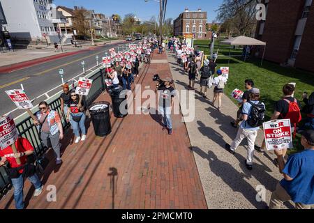 New Brunswick, New Jersey, USA. 12. April 2023. Ein Demonstrant mit einem Megafon führt Gesänge mit Rutgers Studenten und Dozenten an, während sie an einem Streik auf dem Hauptcampus der Universität in New Brunswick teilnehmen. Die drei Fakultätsgewerkschaften, die etwa 9.000 Arbeiter an der Rutgers University, der staatlichen Universität von New Jersey, repräsentierten, streikten, nachdem sie in Verhandlungen mit der Regierung von Rutgers-Präsident Jonathan Holloway keinen Vertrag zustande gebracht hatten. Der Rundgang ist der erste in der 257-jährigen Geschichte der öffentlichen Universität und folgt fast einem Jahr der Verhandlungen um höhere Löhne und B. Stockfoto