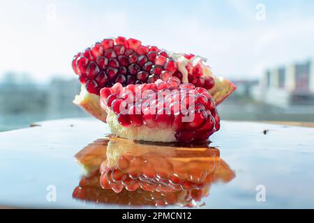 Nahaufnahme von Granatapfel mit seiner leuchtenden roten Farbe. Die kleinen Hülsen sind mit dem süßen erfrischenden Saft gefüllt, der eine tropische Atmosphäre ausstrahlt. Stockfoto