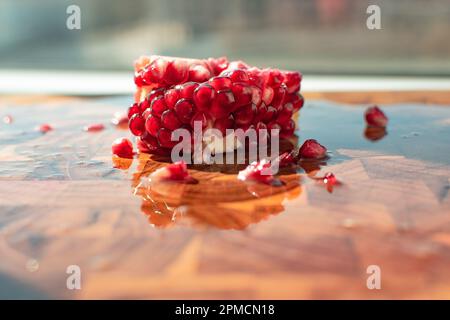 Nahaufnahme von Granatapfel mit seiner leuchtenden roten Farbe. Die kleinen Hülsen sind mit dem süßen erfrischenden Saft gefüllt, der eine tropische Atmosphäre ausstrahlt. Stockfoto