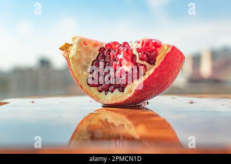 Nahaufnahme von Granatapfel mit seiner leuchtenden roten Farbe. Die kleinen Hülsen sind mit dem süßen erfrischenden Saft gefüllt, der eine tropische Atmosphäre ausstrahlt. Stockfoto