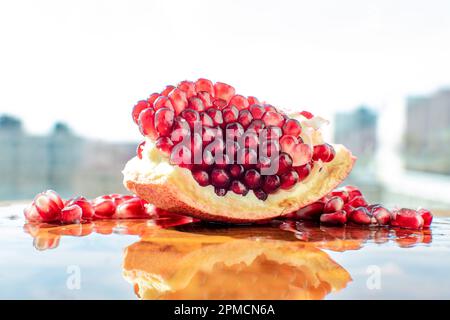 Nahaufnahme von Granatapfel mit seiner leuchtenden roten Farbe. Die kleinen Hülsen sind mit dem süßen erfrischenden Saft gefüllt, der eine tropische Atmosphäre ausstrahlt. Stockfoto