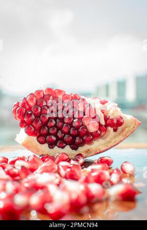 Nahaufnahme von Granatapfel mit seiner leuchtenden roten Farbe. Die kleinen Hülsen sind mit dem süßen erfrischenden Saft gefüllt, der eine tropische Atmosphäre ausstrahlt. Stockfoto