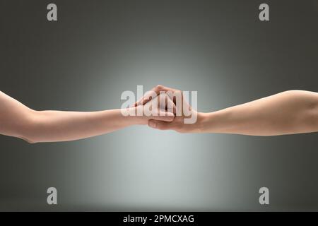 Eine Geste der Zurückhaltung. Die Handfläche eines Mannes, um die Faust einer Frau gewickelt Stockfoto