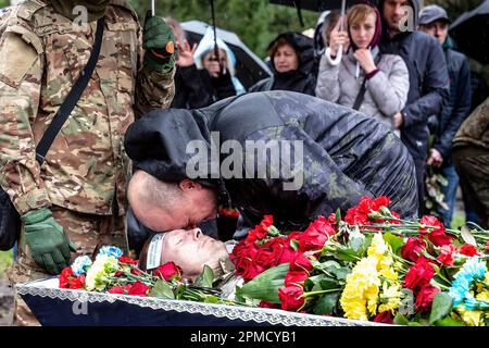 12. April 2023, Kiew, Ukraine: (HERAUSGEBER HINWEIS: Bild zeigt Tod) Ein Freund schenkt Respekt bei der Beerdigung von Evgeny Yakovlev, 42, einem Soldaten, der von russischen Streitkräften an der Ostukrainischen Front in einem Kampf auf dem Lisove Friedhof in Kiew getötet wurde. Auf dem Lisove Friedhof sind die meisten der gefallenen Armeeangehörigen aus Kiew begraben. Da die Invasion der Ukraine in vollem Umfang durch die russischen Streitkräfte andauert, verursacht der Kampf im Osten der Ukraine eine sehr hohe Zahl von Opfern, obwohl die genauen Zahlen unbekannt sind. Die Ukraine bereitet sich auf eine Frühjahrsoffensive zur Rückeroberung des von Russland besetzten Landes vor. (Bild: © Dominika Zarzycka Stockfoto