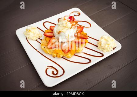 Waffeln mit Schlagsahne, Erdbeeren und Karamellsirup Stockfoto