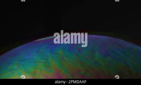 Makro eines irisierenden Seifenblasenfilms, der psychedelische Muster auf schwarzem Hintergrund bildet – abstrakte Farbtextur. Stockfoto