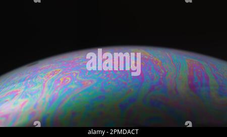 Makro eines irisierenden Seifenblasenfilms, der psychedelische Muster auf schwarzem Hintergrund bildet – abstrakte Farbtextur. Stockfoto