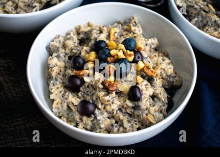 Heidelbeeren-Chia-Haferflocken garniert mit Walnüssen: Gesundes Haferflocken-Frühstück mit Heidelbeeren, Walnüssen und Chiasamen Stockfoto