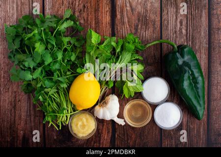 Cilantro-Mint Chutney Zutaten auf einem rustikalen Holztisch: Frische Kräuter, Chili-Pfeffer und andere Zutaten für Cilantro-Minz-Chutney Stockfoto